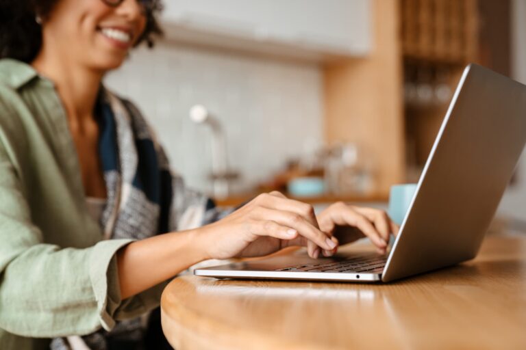 woman typing on laptop at wooden kitchen table taking leadership assessment